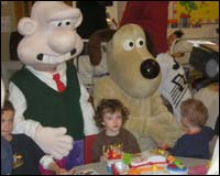 Francis McKnight and Jared McCann face the camera as they receive a cuddle from Wallace and Gromit.